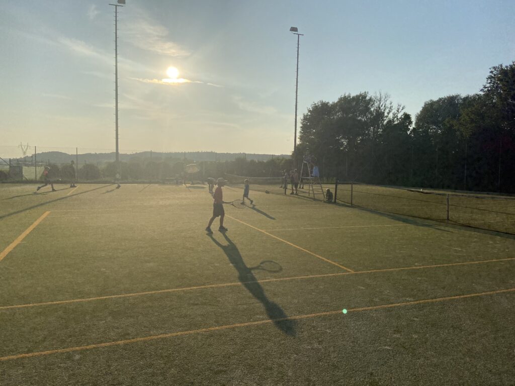 Spieler, die im Sonnenlicht auf einem Tennisplatz des FC Horgau Tennis spielen.